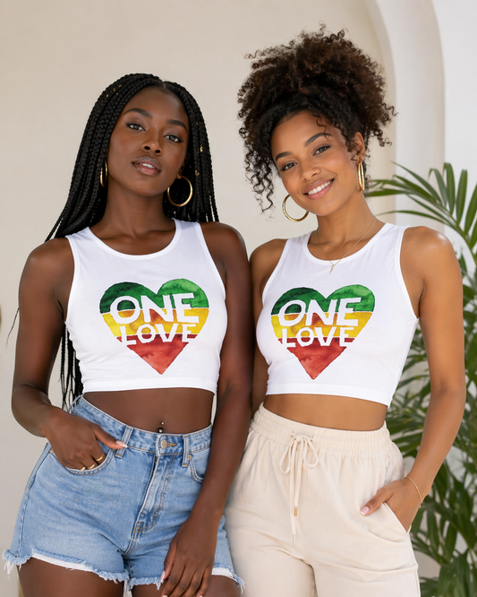 Two women wearing white crop tops with a 'One Love' graphic design, standing outdoors.