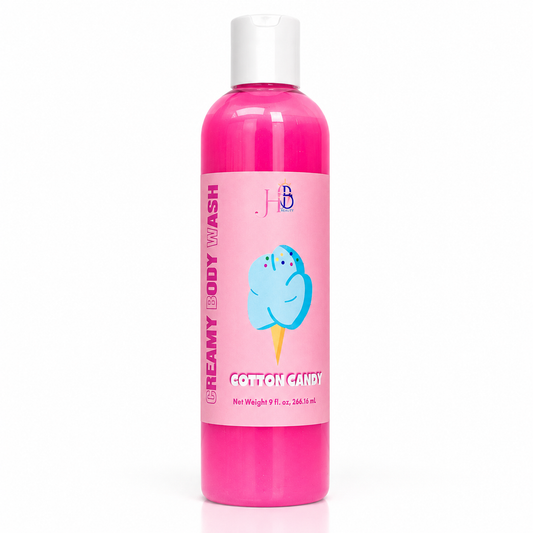 A bottle of Creamy Body Wash in Cotton Candy scent, featuring a bright pink bottle with a white cap and a pink label decorated with a blue cotton candy illustration.