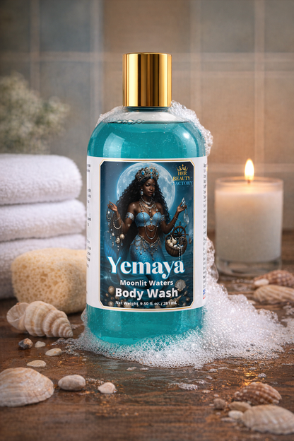 Yemaya body wash bottle with a gold cap on a wooden surface with bubbles, shells, and a candle.