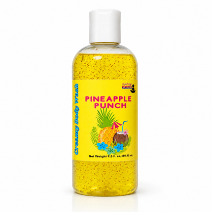 A clear plastic bottle of body wash with a white cap, filled with yellow liquid speckled with glitter. The bottle features a bright yellow label with the text 'PINEAPPLE PUNCH' in pink, along with illustrations of pineapples, coconuts, and tropical flowers.