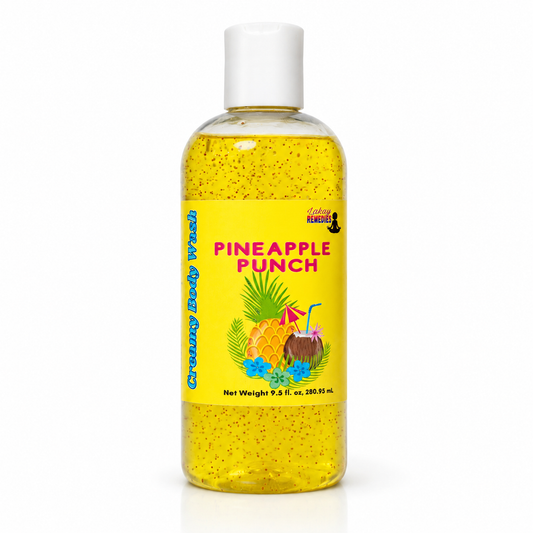 A clear plastic bottle of body wash with a white cap, filled with yellow liquid speckled with glitter. The bottle features a bright yellow label with the text 'PINEAPPLE PUNCH' in pink, along with illustrations of pineapples, coconuts, and tropical flowers.