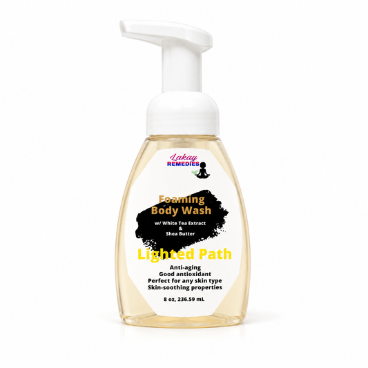 A bottle of Lakay Remedies Foaming Body Wash with a white pump dispenser and a clear bottle showing a pale yellow liquid inside. The label features a black splash graphic with yellow and white text.