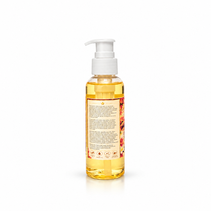 A clear pump bottle filled with golden yellow liquid, showing the back label with text and botanical illustrations, on a white background.