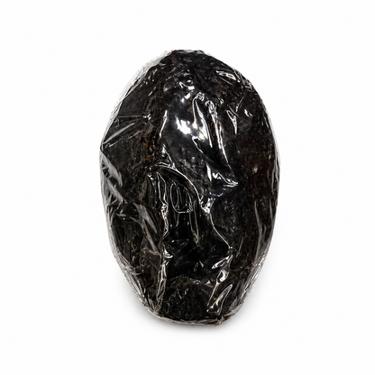 Black vagina candle in clear plastic packaging on a white background