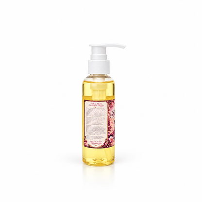 A bottle of Her Beauty Factory Sugar Plum Fairy Body Oil with a white pump dispenser, featuring a pink and purple label with illustrations, set against a plain white background.