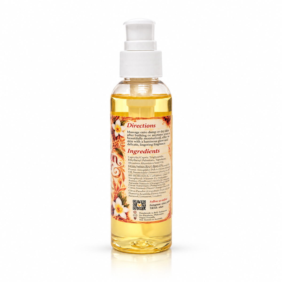 A clear plastic pump bottle filled with golden yellow massage oil, featuring a white pump dispenser and a detailed label with orange and white floral illustrations and text, set against a plain white background.