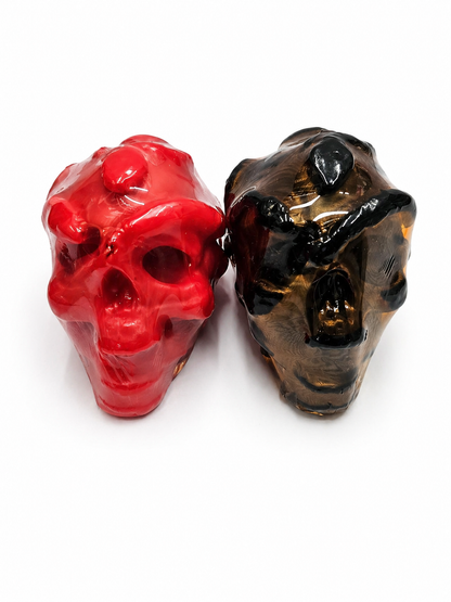 Two red and black skull-shaped candle on a white background