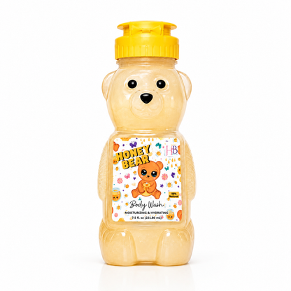 A honey bear-shaped body wash bottle with a yellow flip-top cap, filled with golden honey-colored liquid. The bear-shaped bottle features a printed front label that reads 'HONEY BEAR Body Wash' with a teddy bear illustration and small colorful flower accents.