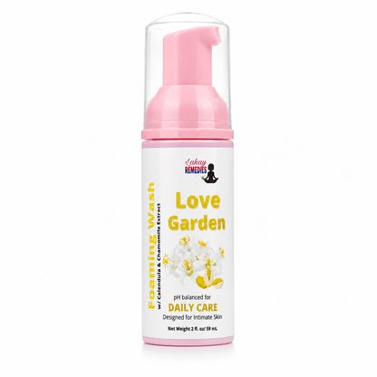 A bottle of Love Garden Foaming Wash, featuring a pink pump dispenser and a white label with yellow text and floral graphics, set against a plain white background.