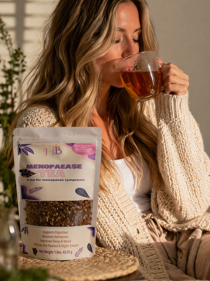 Woman drinking tea with a package of Menopaaease tea in front of her