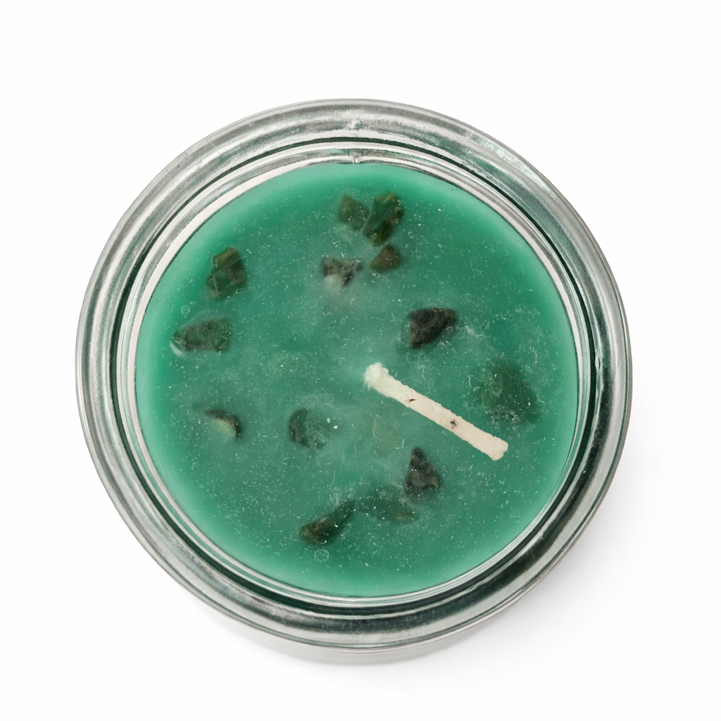 Green candle with visible wick in a glass jar on a white background