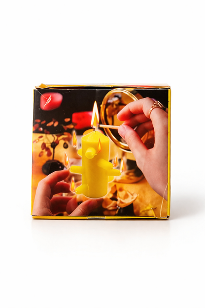Yellow candle shaped like a fire hydrant with a hand lighting it, displayed against a decorative box background.