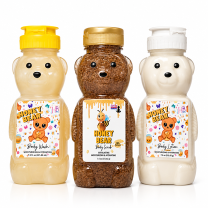 Three bear-shaped body wash, scrub and lotion bottles on a white background: a pale yellow bottle labeled Honey Bear Body Wash with a yellow cap, a medium brown bottle labeled Honey Bear Body Scrub with a gold cap, and a creamy off-white bottle labeled Honey Bear Body Lotion with a white cap.